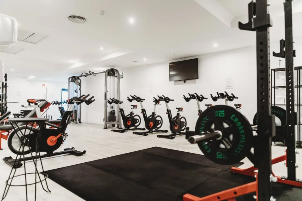 Sala del gimnasio con máquinas, bicicletas y rack de sentadillas
